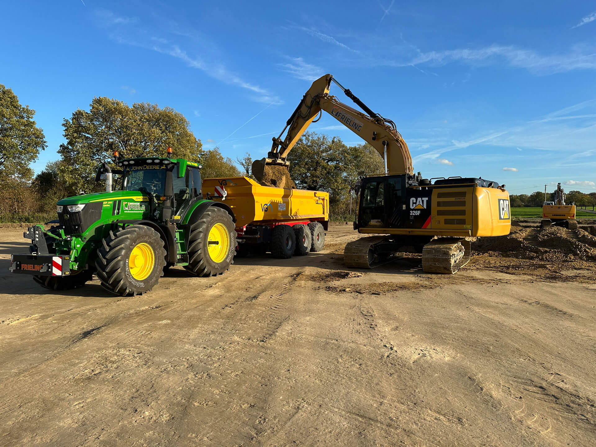 Bagger belädt Traktor mit Erde